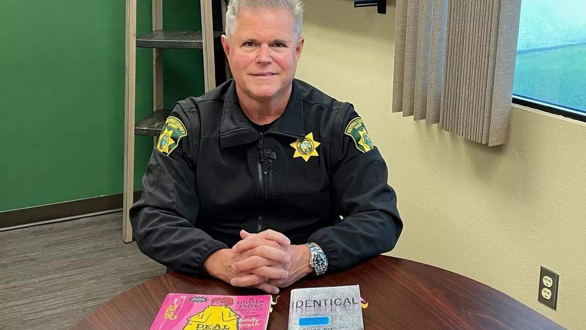 Kootenai County Sheriff Bob Norris poses with books he said he found offensive and wants to keep off library shelves. He denied that this amounted to banning books.