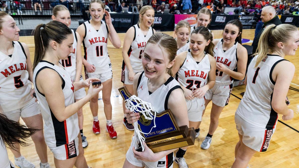 Melba’s Hallie Arnold holds the 2A girls basketball state championship trophy with her teammates after a 55-46 win over Soda Springs on Saturday at the Ford Idaho Center in Nampa.