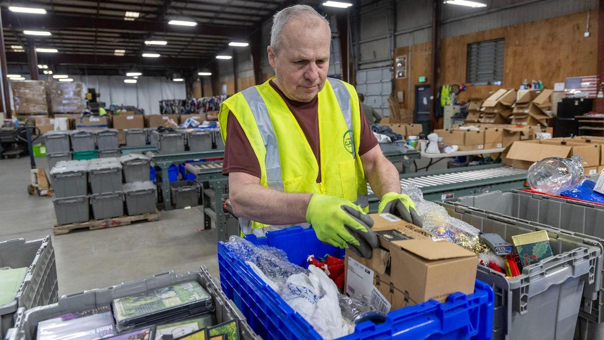 Idaho Youth Ranch worker Paul Schilli sorts through bins of donated items that are categorized and prepared for distribution at the outlet warehouse in Boise.