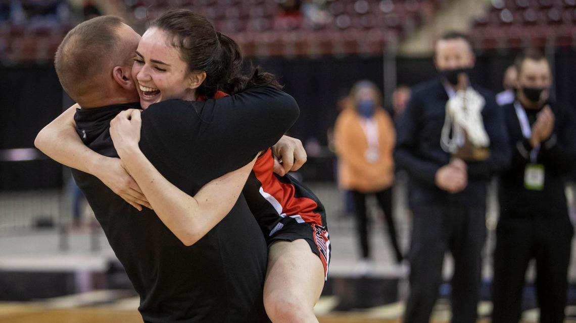 Melba senior Kate Clark leaps into the arms of head coach David Lenz after the Mustangs won their first state championship Saturday at the Ford Idaho Center.
