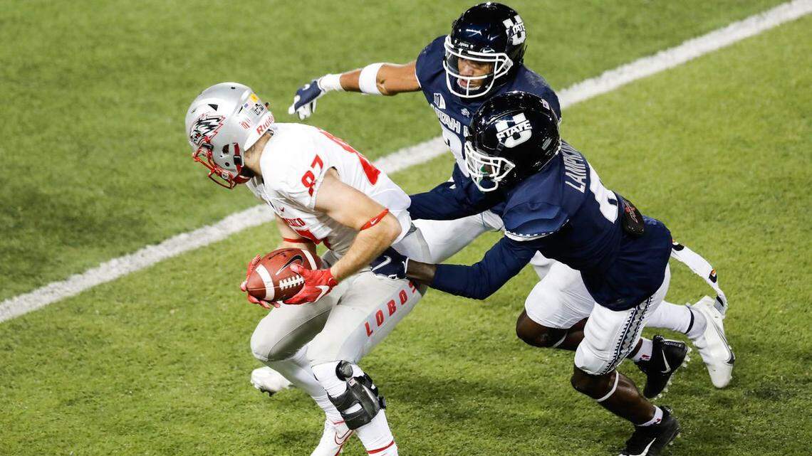 Former Utah State defensive back Jared Reed, top, and teammate Cam Lampkin tackle New Mexico wide receiver Andrew Erickson during a game last season. Reed announced Wednesday that he will transfer to Boise State.