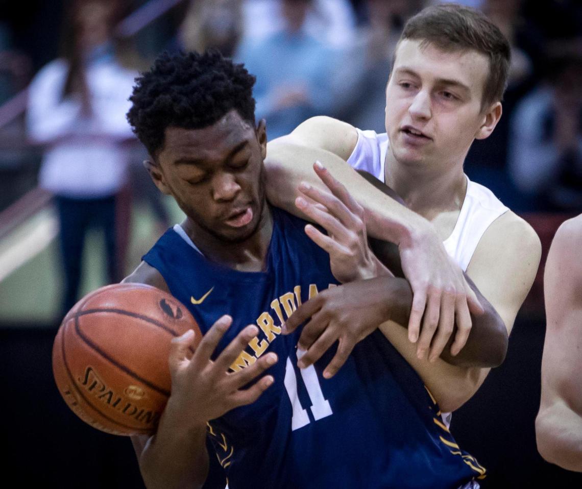 Meridian guard Davis Thacker takes an elbow from Lake City’s Nathan Spellman in the 5A boys basketball state championship Saturday at the Ford Idaho Center in Nampa.