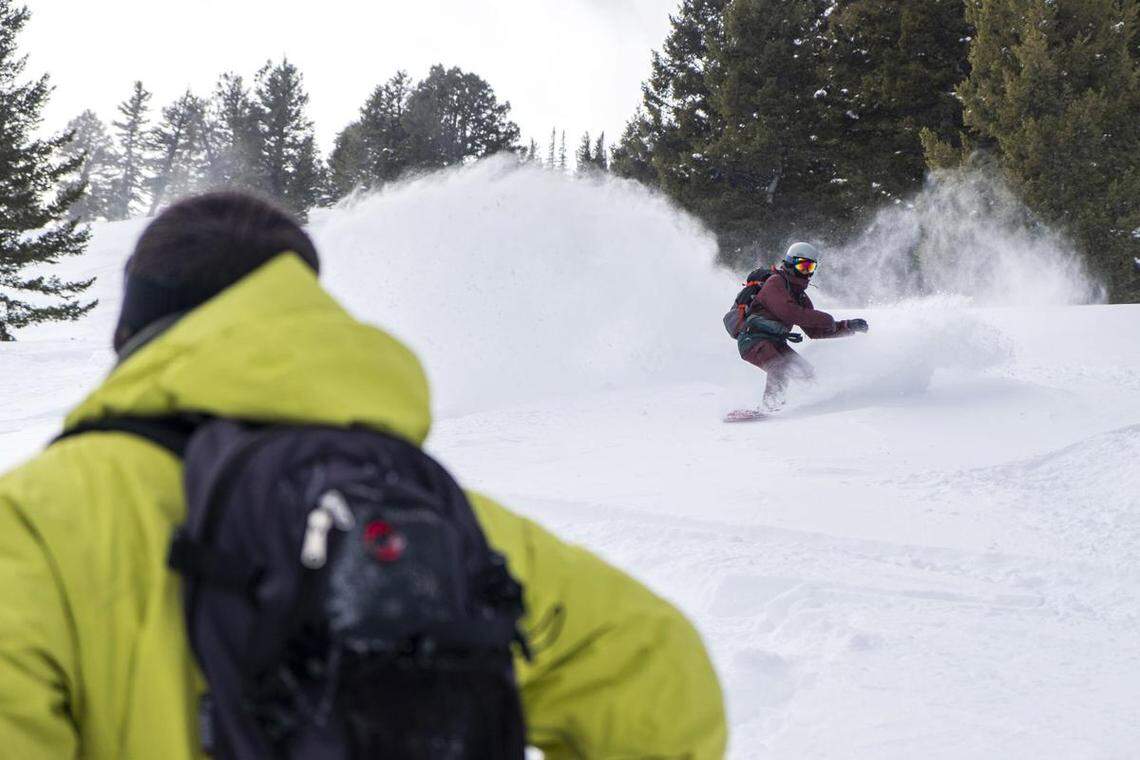 Skier Mario Brusa watches snowboarder Meredith Richardson slash powder snow at the end of ‘The Triangle’ run while on a Cat skiing trip Sunday. Feb. 21 at Soldier Mountain Resort north of Fairfield.