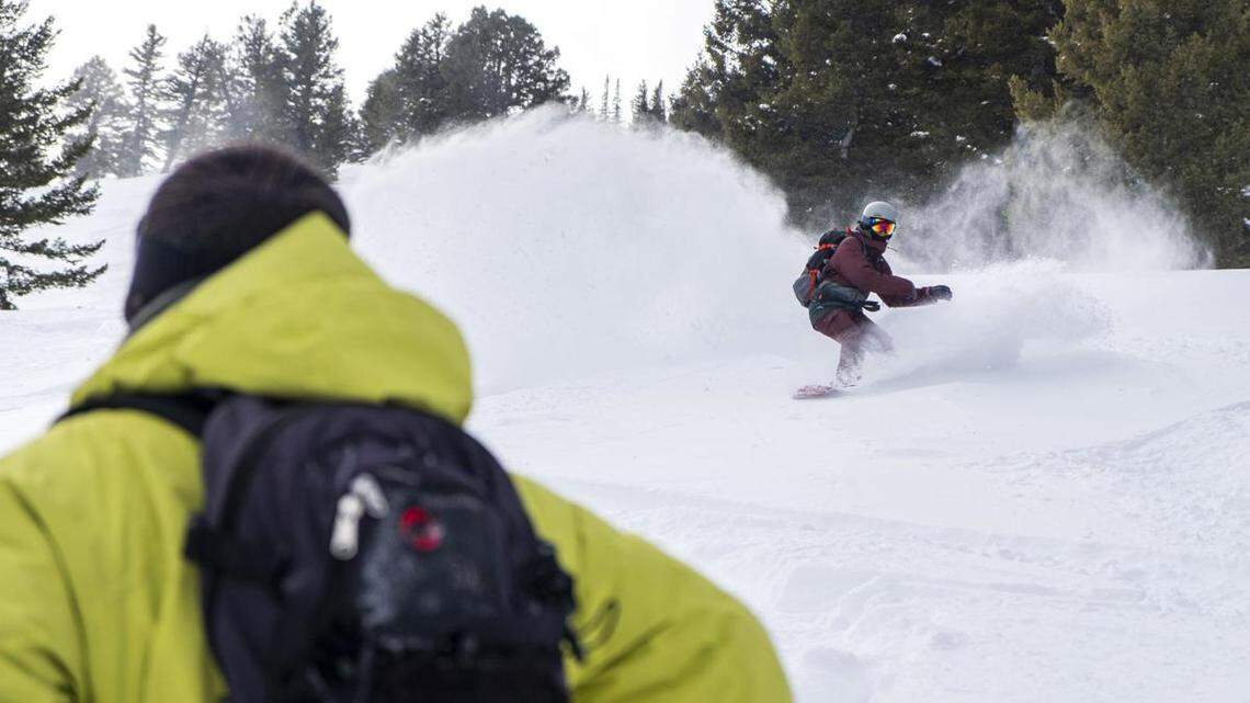 Skier Mario Brusa watches snowboarder Meredith Richardson slash powder snow at the end of ‘The Triangle’ run while on a Cat skiing trip Sunday. Feb. 21 at Soldier Mountain Resort north of Fairfield.