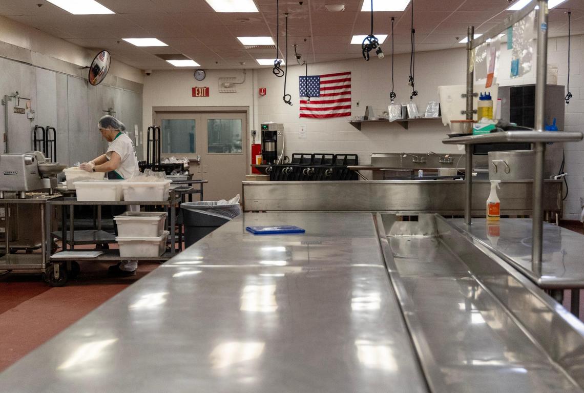 A jail resident works in the kitchen to prepare lunch.