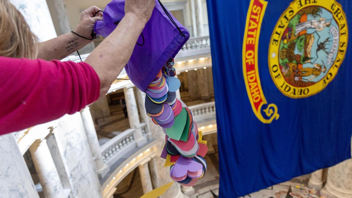 AlexaLynne Fill, of Nampa, dumps one of several bags of handmade paper hearts, totaling over 48,000, from the fourth floor of the Idaho Capitol rotunda during a demonstration by members of the LGBTQ+ community, Tuesday, April 2, 2024.