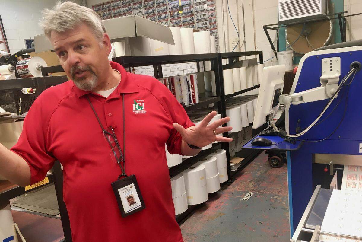 Job training specialist Matt DeTour stands by the machine that manufactures Idaho’s required invasive species inspection stickers for boats. He believes in the power of apprenticeships to change Idaho State Correctional Institution residents’ future. “These guys are really talented,” he said.