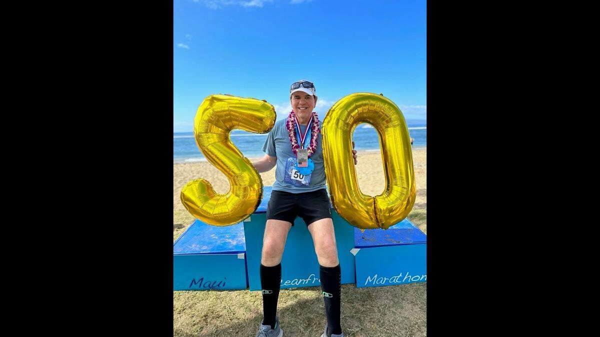 Bob Mueller poses with balloons at the end of the Maui Oceanfront Marathon on Jan. 15, 2023, after finishing the race. It marked the final race he needed to run a marathon in each state.
