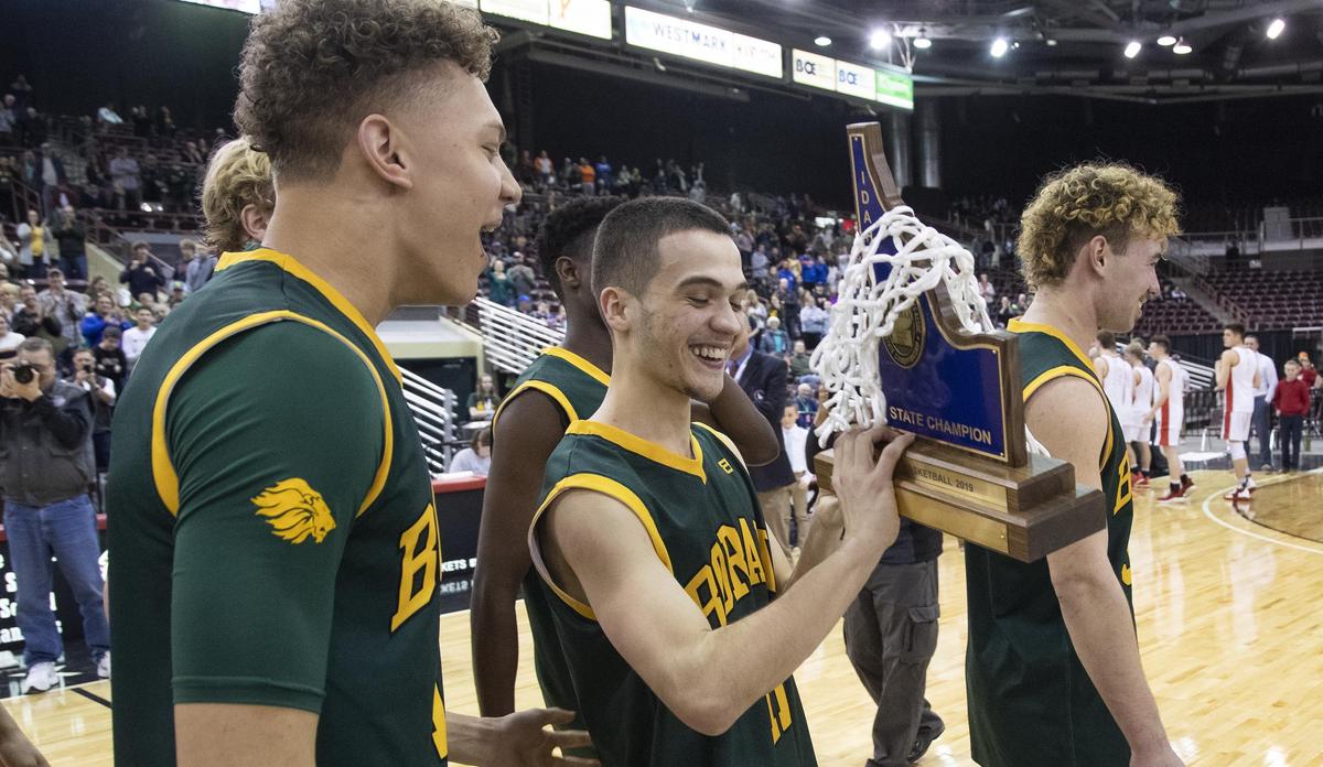 Borah seniors Kyler Castro, center, and Caleb Golden admire the state 5A boys basketball trophy as they are announced as champions Saturday, March 2, 2019 at Ford Idaho Center in Nampa.