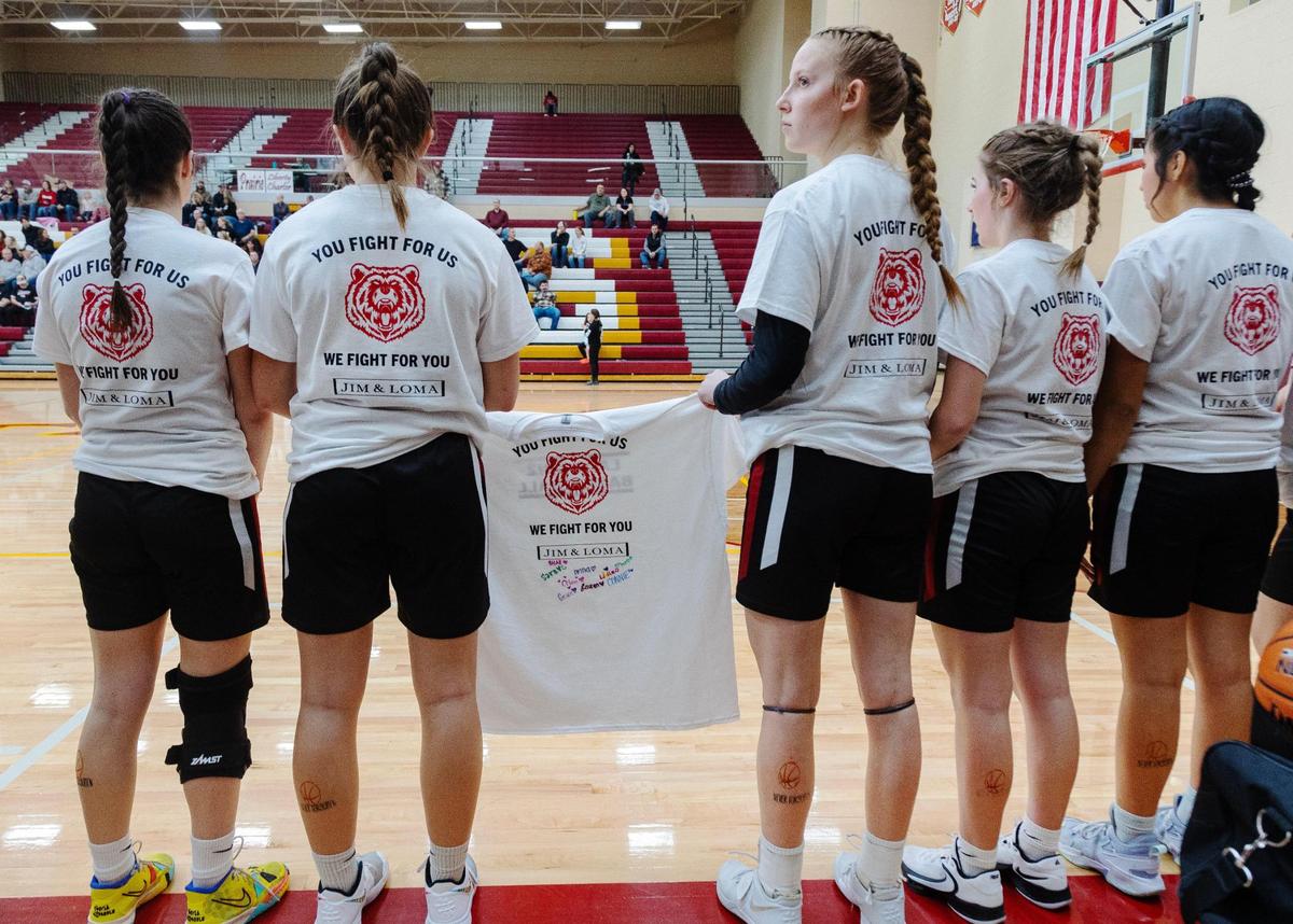 Players on the Greenleaf Friends Academy girls basketball team wear shirts and temporary tattoos in their legs in honor of the death of their coaches.