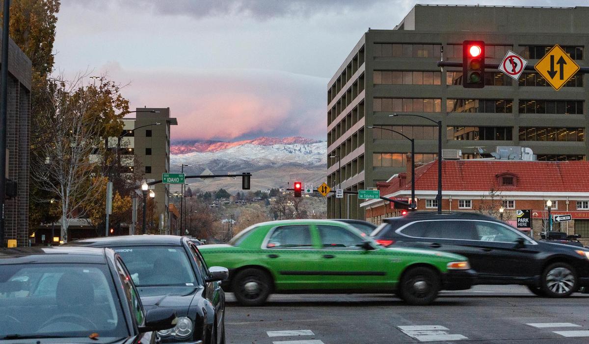 A green car from Boise City Taxi drives on Main Street in downtown Boise. 