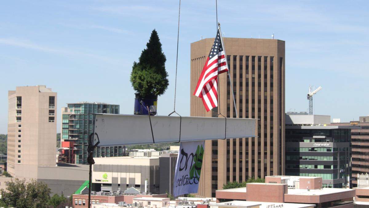 The last beam, with a small evergreen tree and an American flag on top of it, is hoisted up to the two-tower Idaho Central Credit Union Plaza under construction in downtown Boise. Ceremony-goers and construction workers got a chance to sign the beam.