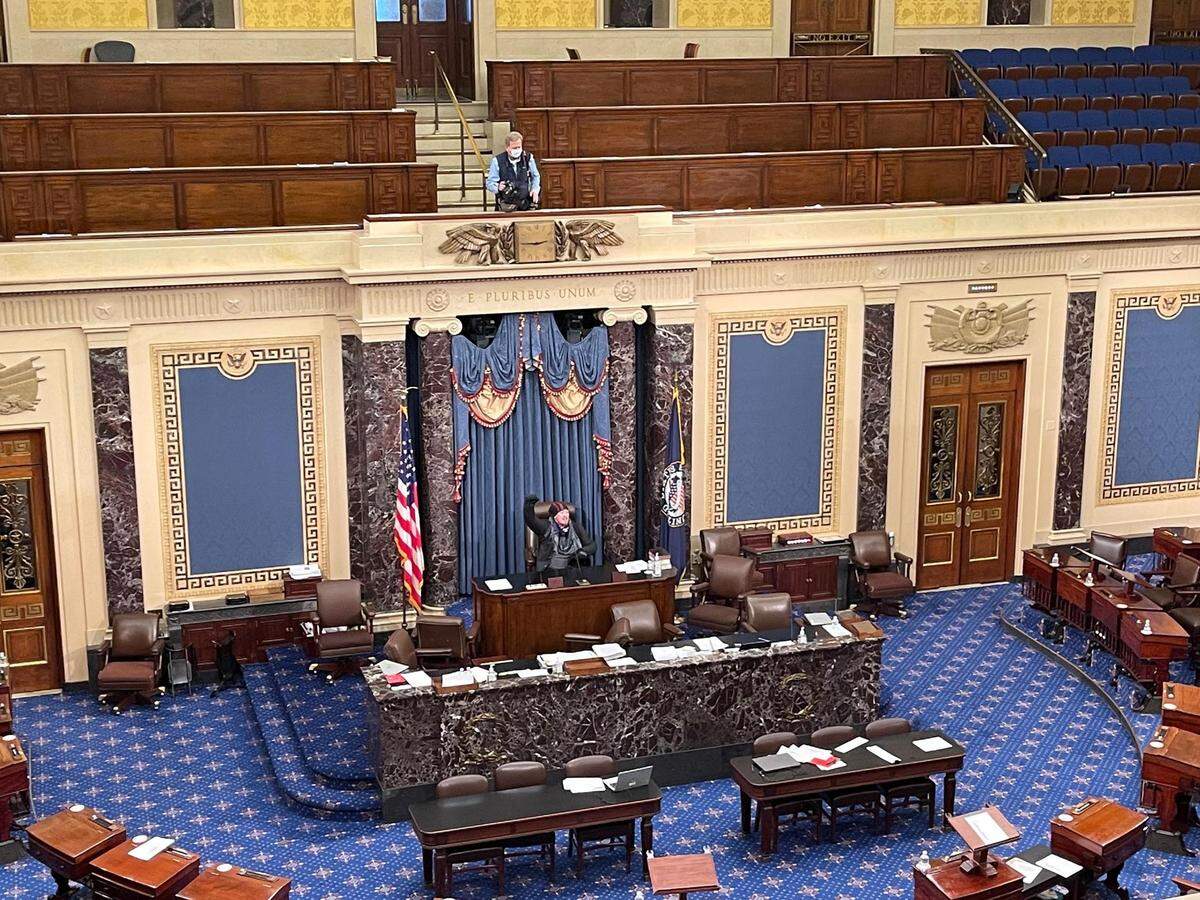 Treasure Valley resident Josiah Colt, who later posted on social media that he was part of the group storming the U.S. Capitol, raises a fist in the Senate chamber. He later apologized for his actions.