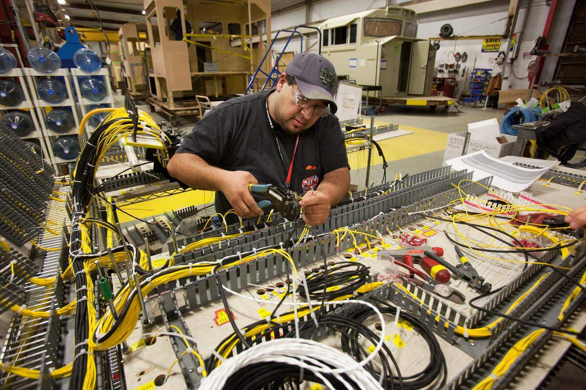 Bryan Gonzales, locomotive electrician, assembles an electrical harness for the high voltage cabinet in a locomotive bound for Australia in 2012.