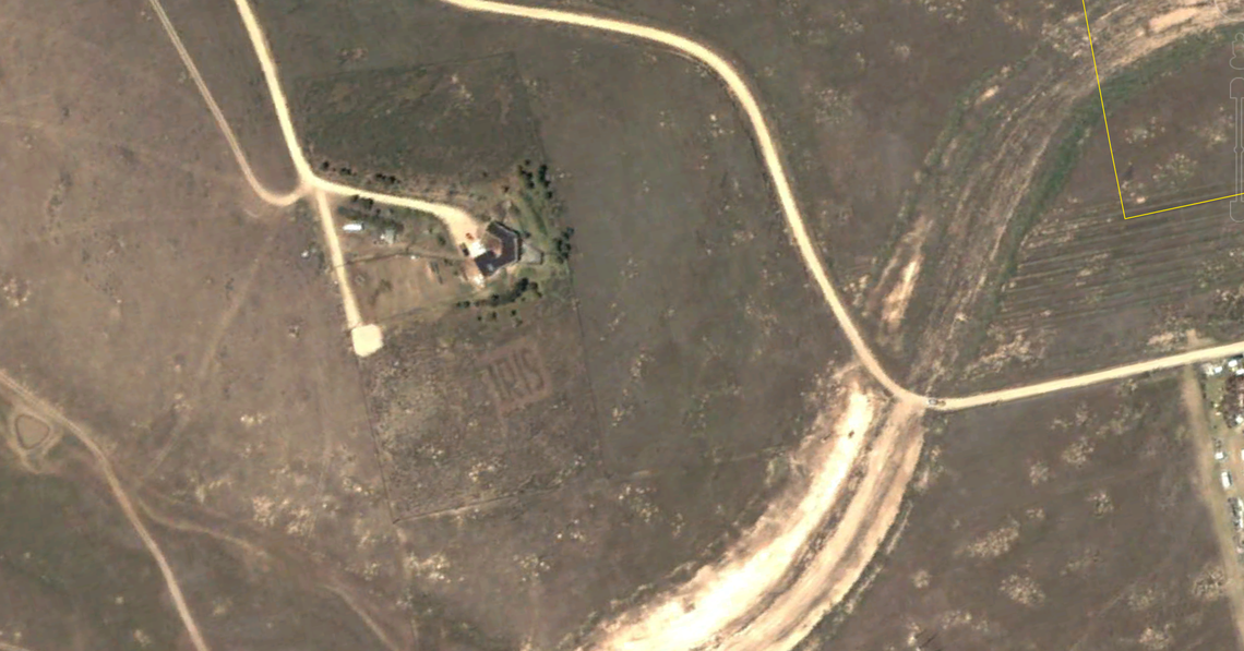 A Google Earth screengrab from June 2002 shows a message reading IRIS pruned into sagebrush at a Boise home across Interstate 84 from Micron. The sign, which Google measurements estimate was about 85 feet tall, was an advertisement for the homeowner’s flower business.