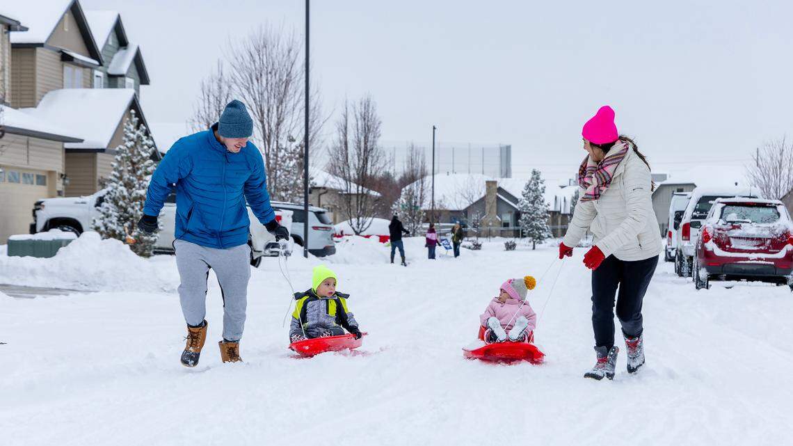 Muharem and Monica Ahmetovic pull their children Zayd, 3, and Izabel, 1, in sleds through the snow on their street in Meridian on Sunday.