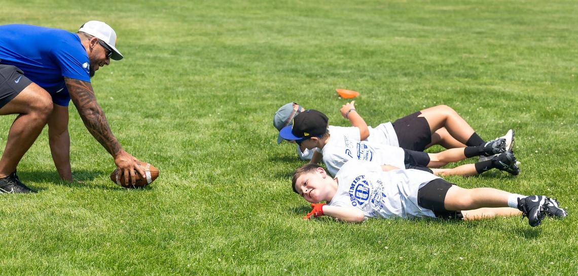 Boise State defensive end Ahmed Hassanein, left, coaches kids as they roll across the grass for a drill at the Optimist Youth Football Kids Skills Camp on Saturday in Boise.