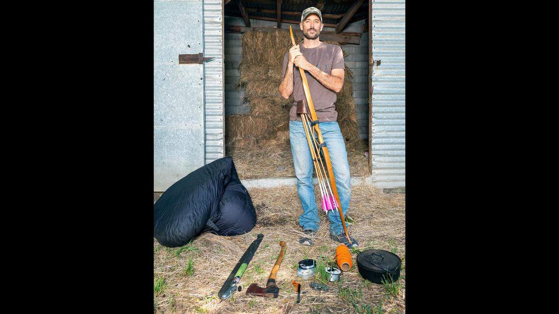 Clay Hayes, of Kendrick, poses with 10 belongings he was allowed to take on the television show “Alone” while at his home on Wednesday. Last Fall Hayes — an avid outdoorsman, bow maker and videographer — competed in the eighth season of “Alone” which took place at Chilko Lake in British Columbia. Contestants are only allowed to bring 10 items with them and are challenged to survive in the wilderness by themselves for as long as possible. The winner is awarded $500,000.
