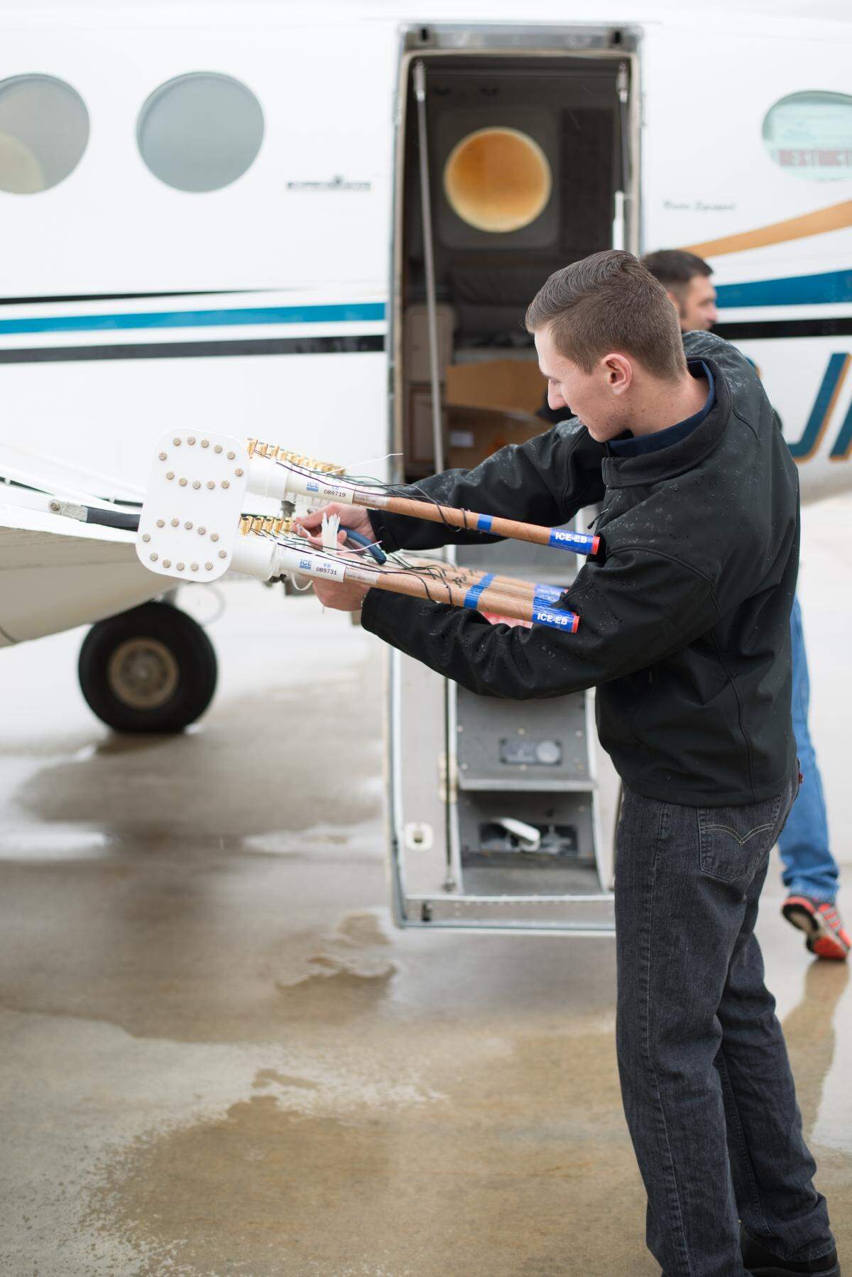 A contract pilot for Weather Modification Inc. prepares to install cloud seeding flares under the wings of an aircraft at the Boise Airport.