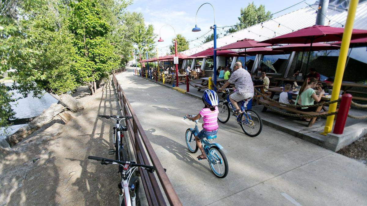As cyclists pass on the Greenbelt, customers enjoy pleasant weather on the patio of Joe’s Crab Shack in 2015.