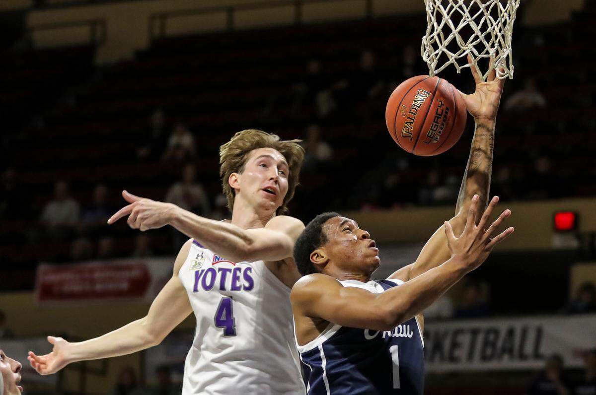 The College of Idaho’s Tyler Robinett, left, defends a shot from Ethan Williams of Oklahoma Wesleyan in Tuesday’s NAIA national championship game at Municipal Auditorium in Kansas City.