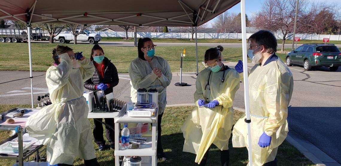 Health care workers in personal protective equipment work out of Saint Alphonsus’s Meridian Health Plaza at a respiratory assessment site.