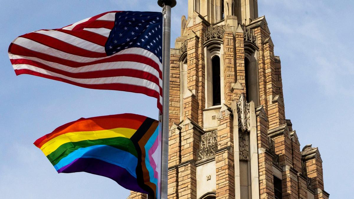 A Progress Pride Flag below the U.S. Flag waves in the wind in front of the Cathedral of the Rockies Boise First Methodist Church.