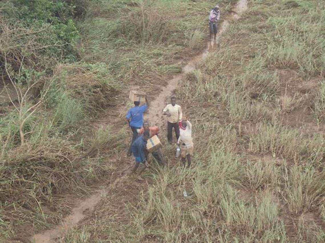 A group carrying boxes waves as a plane from the Mission Aviation Fellowship passes above.