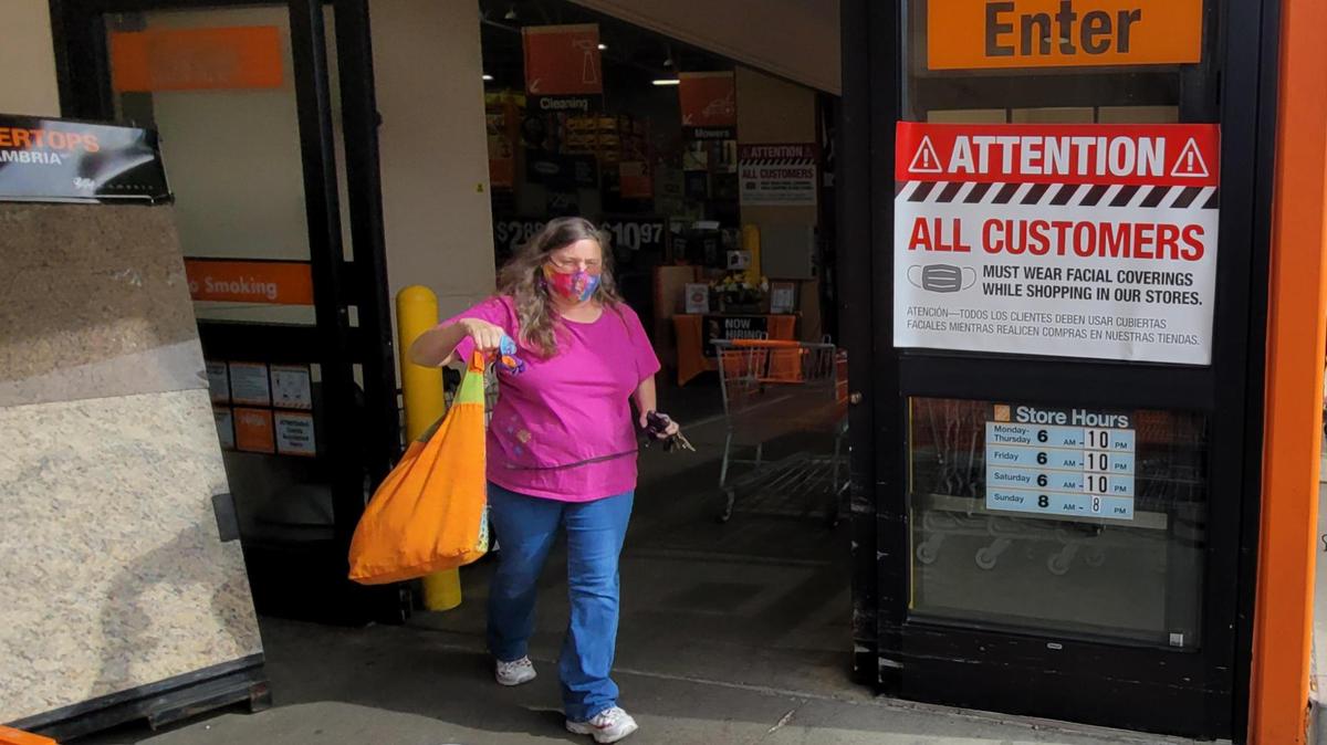 A woman leaves the Boise Home Depot store wearing a mask Saturday. The home improvement store continues to require customers to do so.
