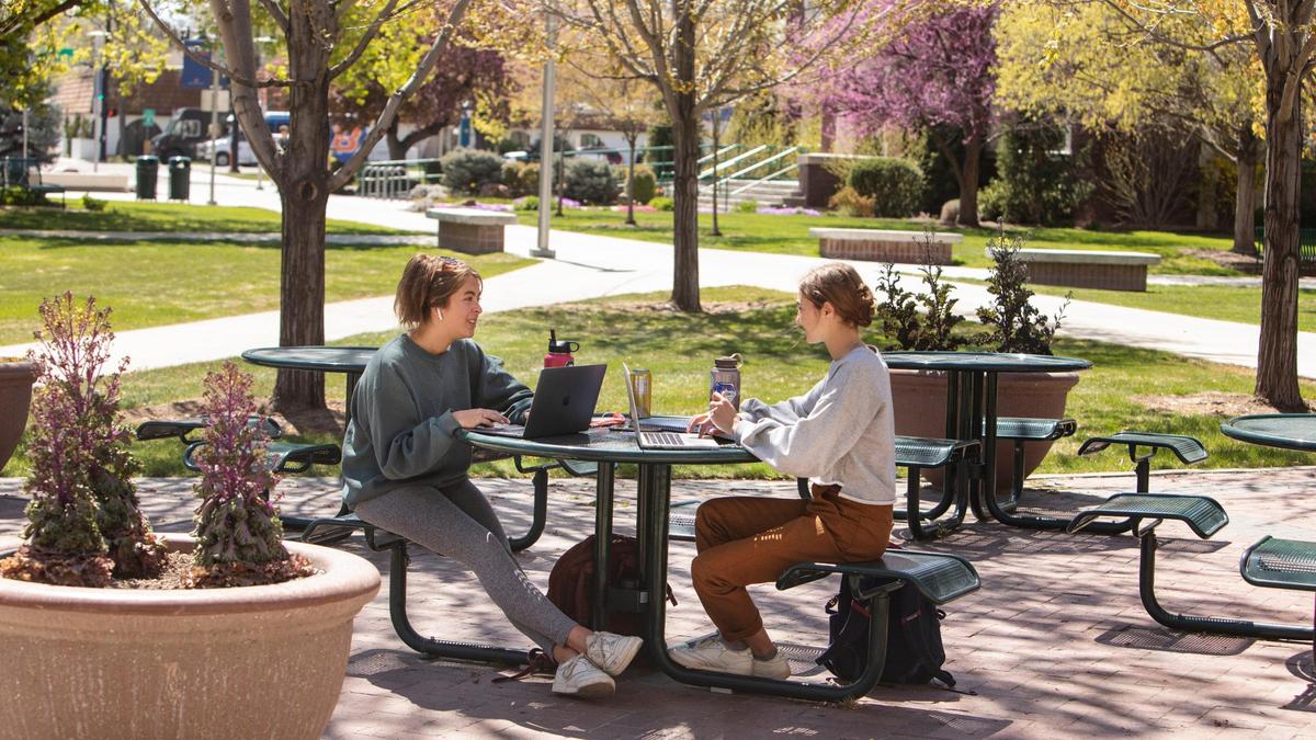 Honors College students Elena Phillips of Vancouver, Wash. and Emma Thomas of Salt Lake City, Utah, sit together as they use their laptops in April outside the Albertsons Library at Boise State University.