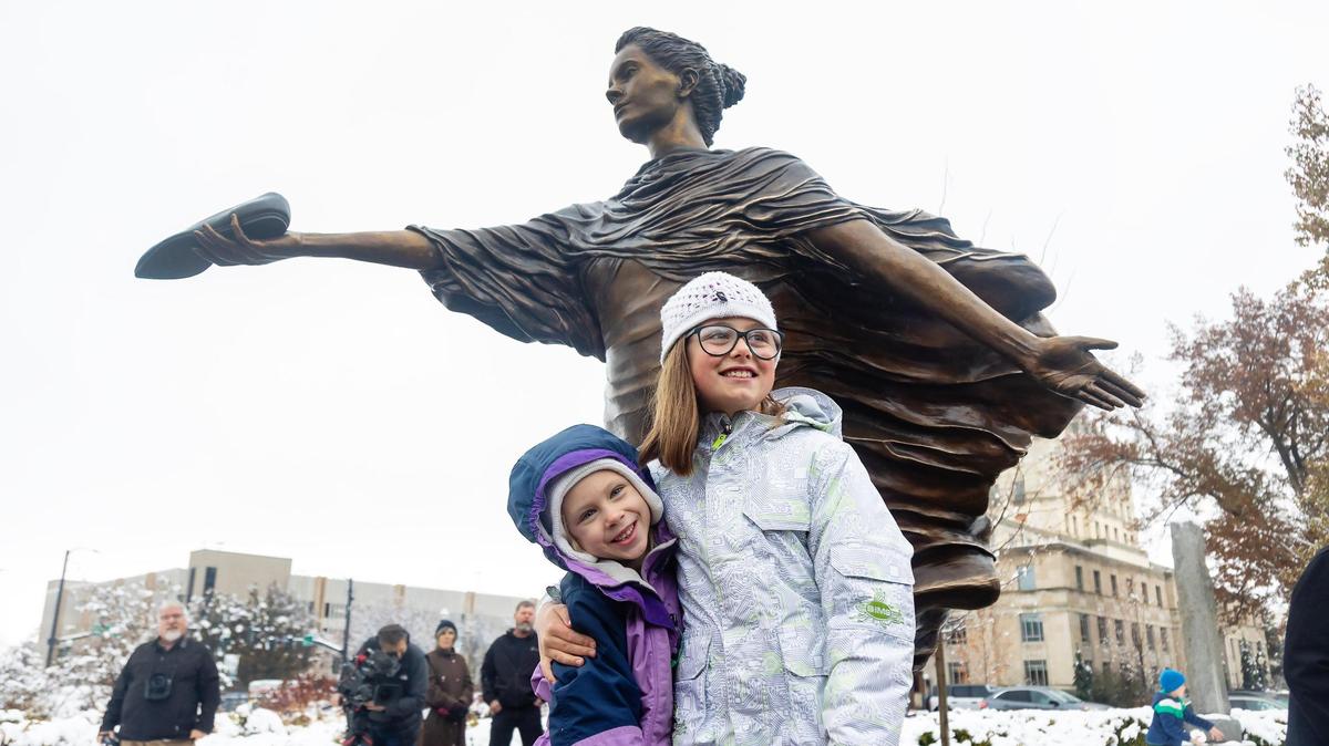 Halle Deely and Priscilla Angelos pose in front of a new statue created by Deely’s grandmother, Irene Deely, and located on the grounds of the Statehouse.