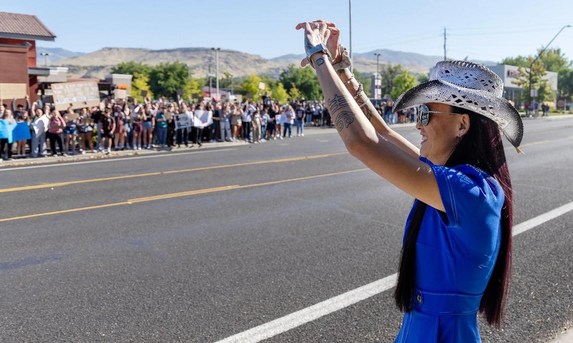 Laura Boulton holds her hands in the shape of a heart and tells a crowd of several hundred students lining the sidewalk across from Timberline High School “I love you” during the walkout.
