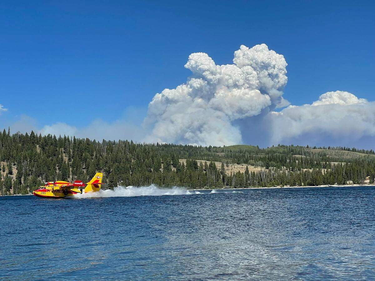 A plane dips water out of Redfish Lake to carry to the Wapiti wildfire.