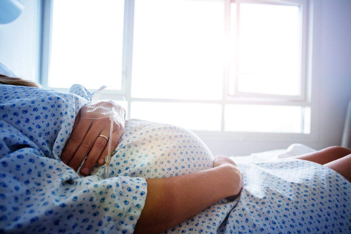Close-up of a pregnant woman’s belly in the hospital bed.