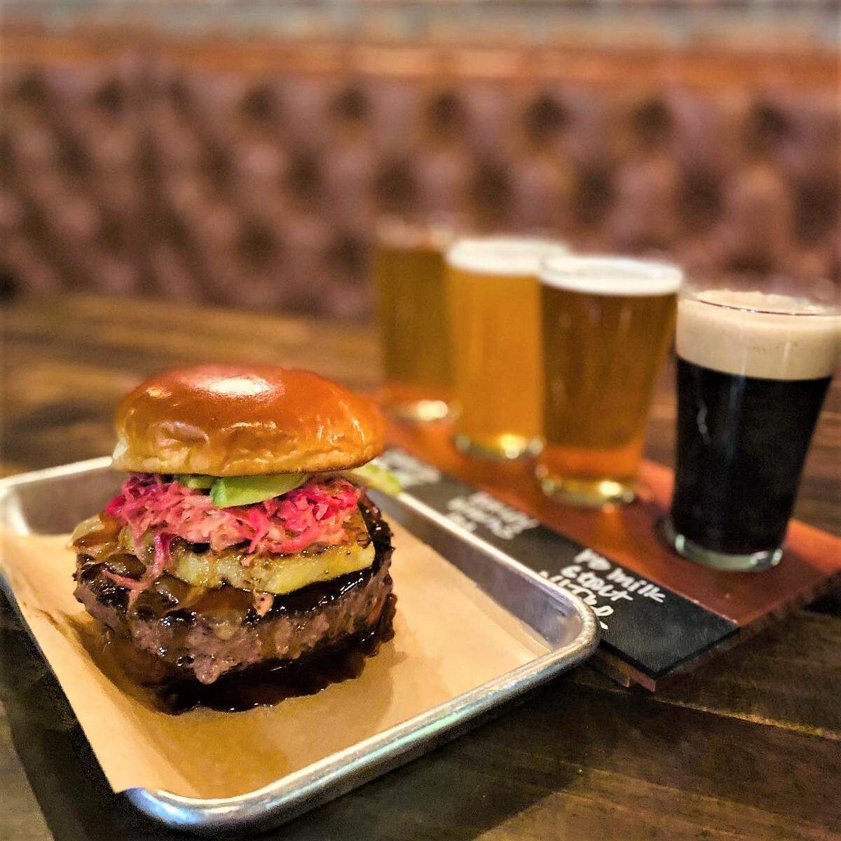 The half-pound Maui Wowie Burger and a beer flight shown at Sid’s Garage in Meridian.