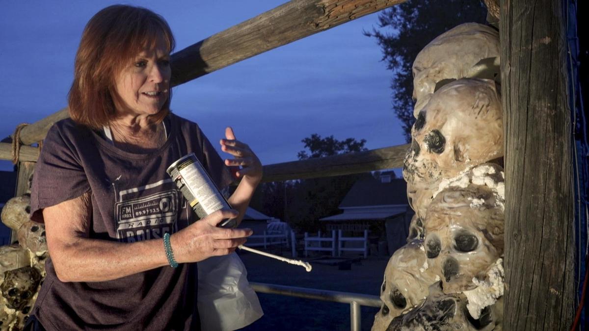 Volunteer Cindy Sawyers helps build wall of skulls using milk jugs that were melted over a mold and painted.