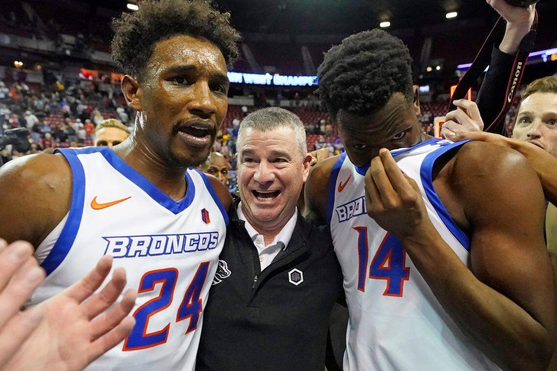 Boise State’s Abu Kigab (24) and Emmanuel Akot celebrate with coach Leon Rice after winning the Mountain West Tournament championship.