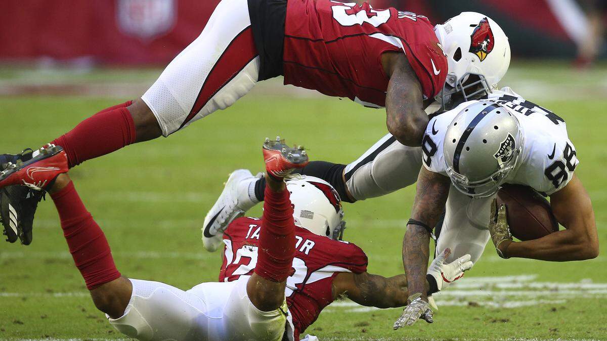 Arizona Cardinals linebacker Haason Reddick, top, and cornerback Jamar Taylor tackle Oakland Raiders wide receiver Marcell Ateman during the first half Sunday  in Glendale, Ariz.