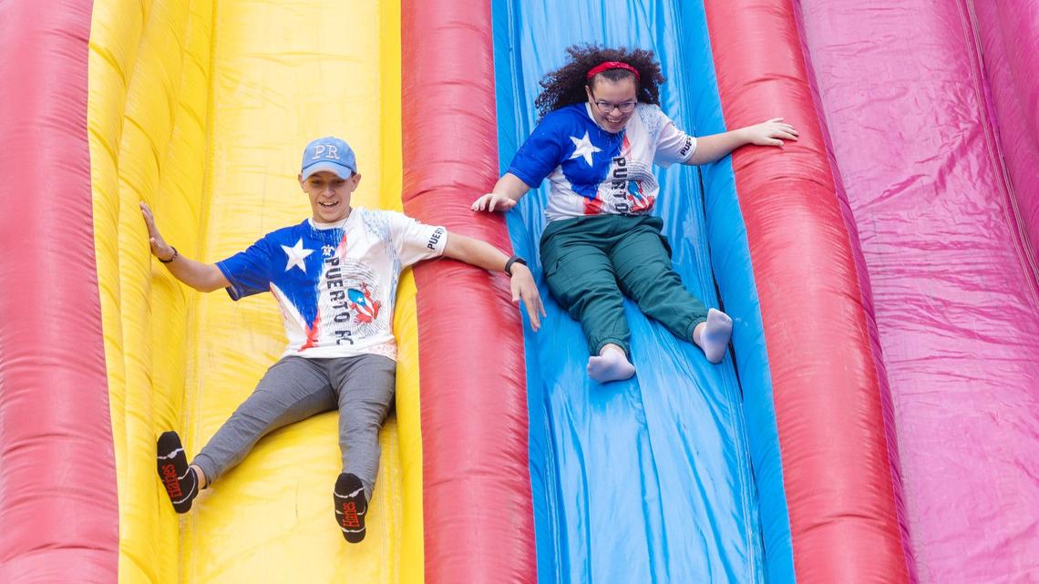 Siblings Diego Irizarry-Pietri and Alana Irizarry-Pietri wear matching Puerto Rico shirts as they ride a slide at Latino Fest in at Cecil Andrus Park downtown Boise on Saturday.