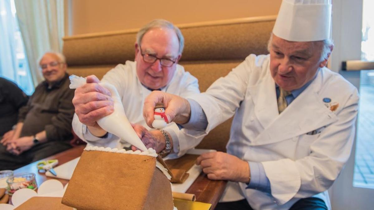 Mark Ramsdell, left, and former White House executive pastry chef Roland Mesnier demonstrate how to build a classic gingerbread house.