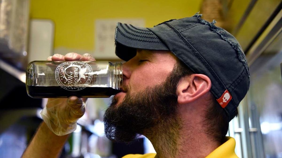 Adam Armstrong, owner of Pure Juice Bar, savors a sip of his charcoal lemonade.
