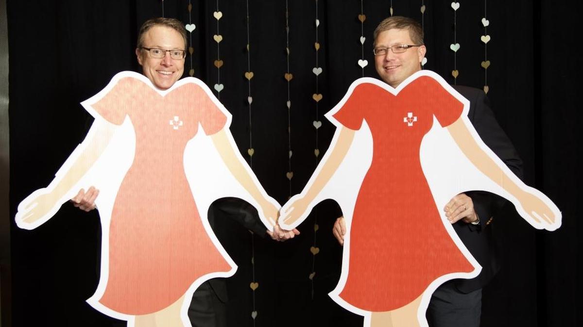 Saint Alphonsus and St. Luke’s heart administrators Tom Reinhart and David Bishop support Idaho Go Red week with cutout red dresses.
