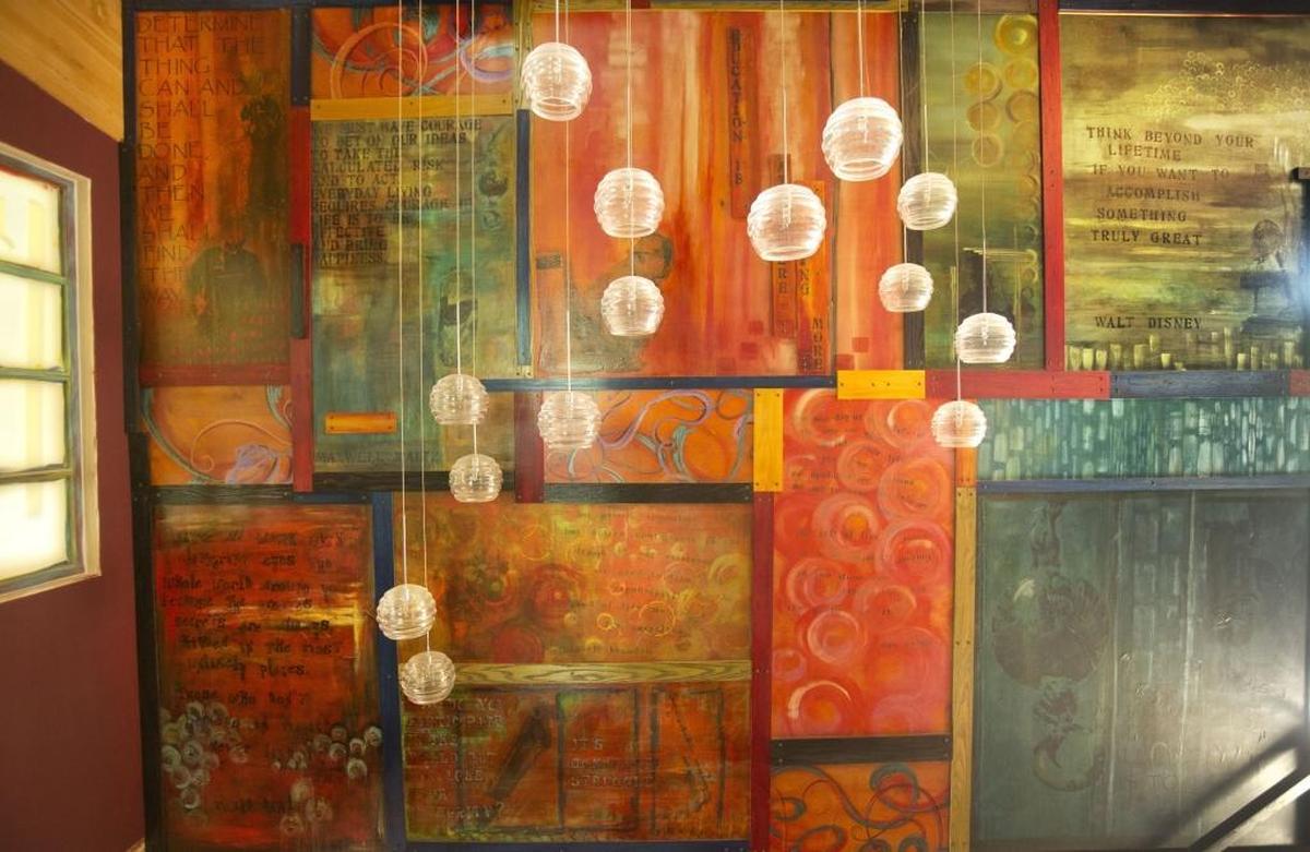 Debbie Lombard-Bloom liked a cost-prohibitive glass chandelier, so she made her own version lighting the stairway wall. At the far right is a portrait of Gerry Bloom placing the beam for the home remodel. Next to that is the Disney quote that Debbie painted on an upstairs wall: “Think beyond your lifetime if you want to accomplish something truly great.”