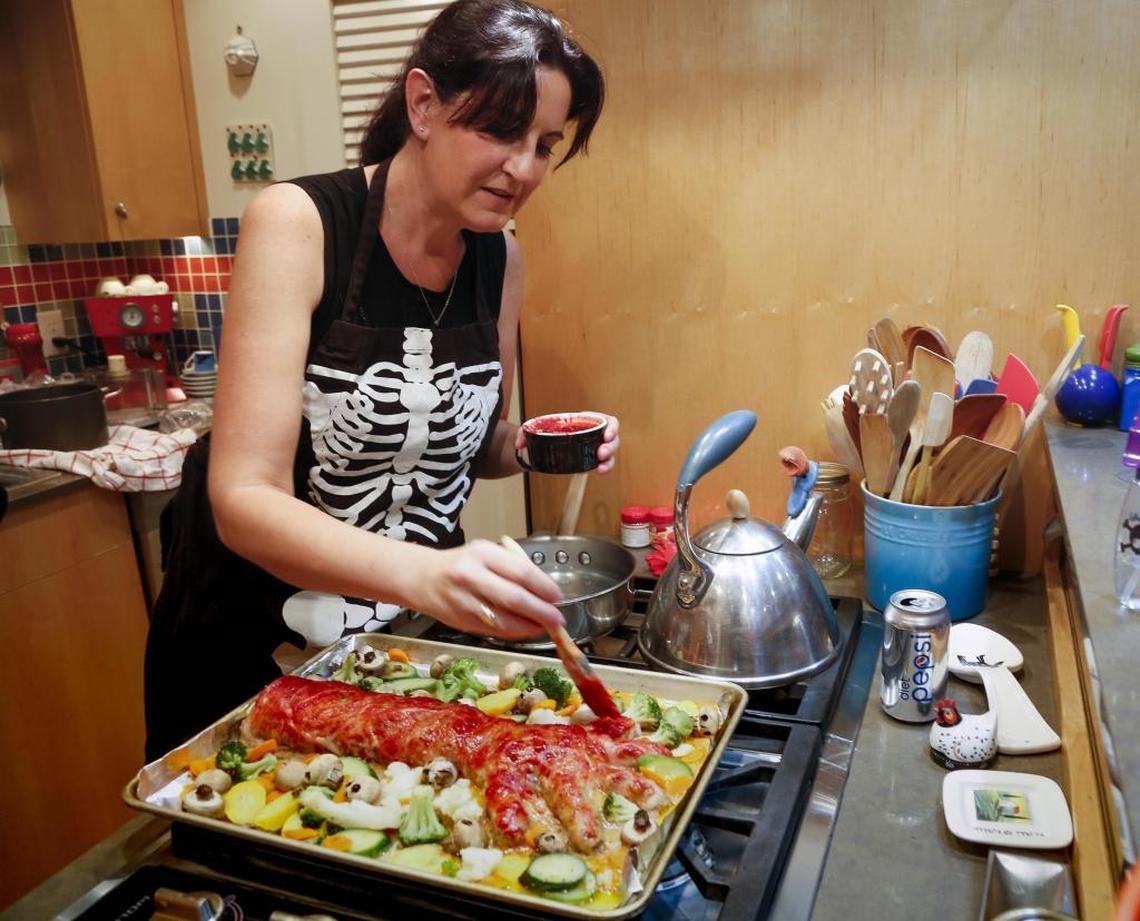 Beckie Lombardi bastes her Zombie Arm Meat Loaf with gooey red sauce. Several nights each week Lombardi creates creepy dinners to try out the recipes.