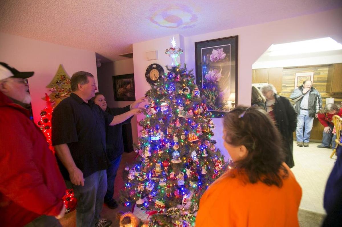 Hank Nystrom, left of center, shows off on of his decorated trees at last year’s Tree Trimmers Collectors Club tour. He founded the group, which also has a community service component, more than a decade ago for people passionate about Hallmark ornaments.