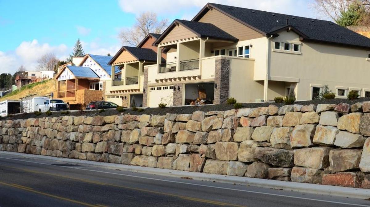 Boulders form a retaining wall between the North Hill homes and Hill Road. A second retaining wall is located behind the homes.