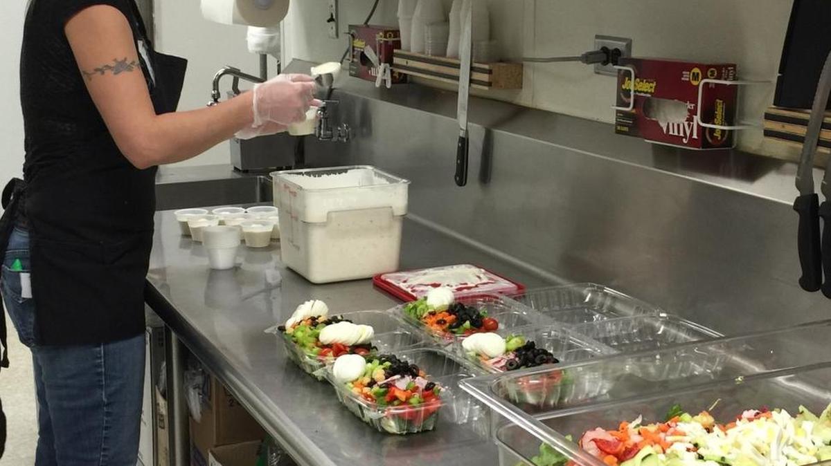 A cafeteria worker prepares salads to go for teachers and students who will eat in their classrooms.