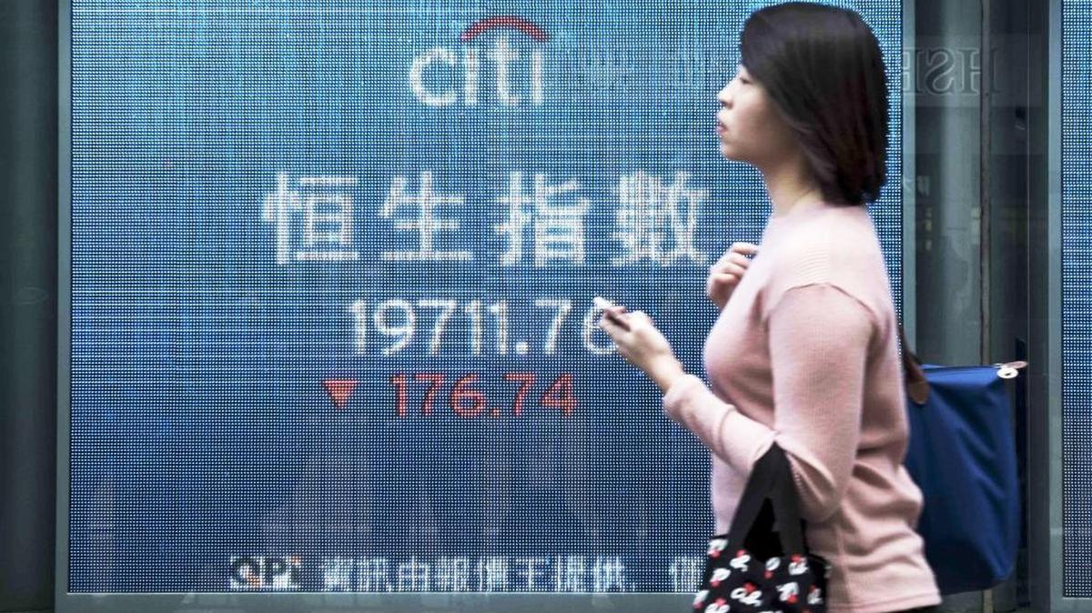 A pedestrian walks past an electronic screen displaying stock exchange index information in Hong Kong on Jan. 12. China has stepped up its defense of the yuan, buying the currency in Hong Kong to deter bearish speculators.