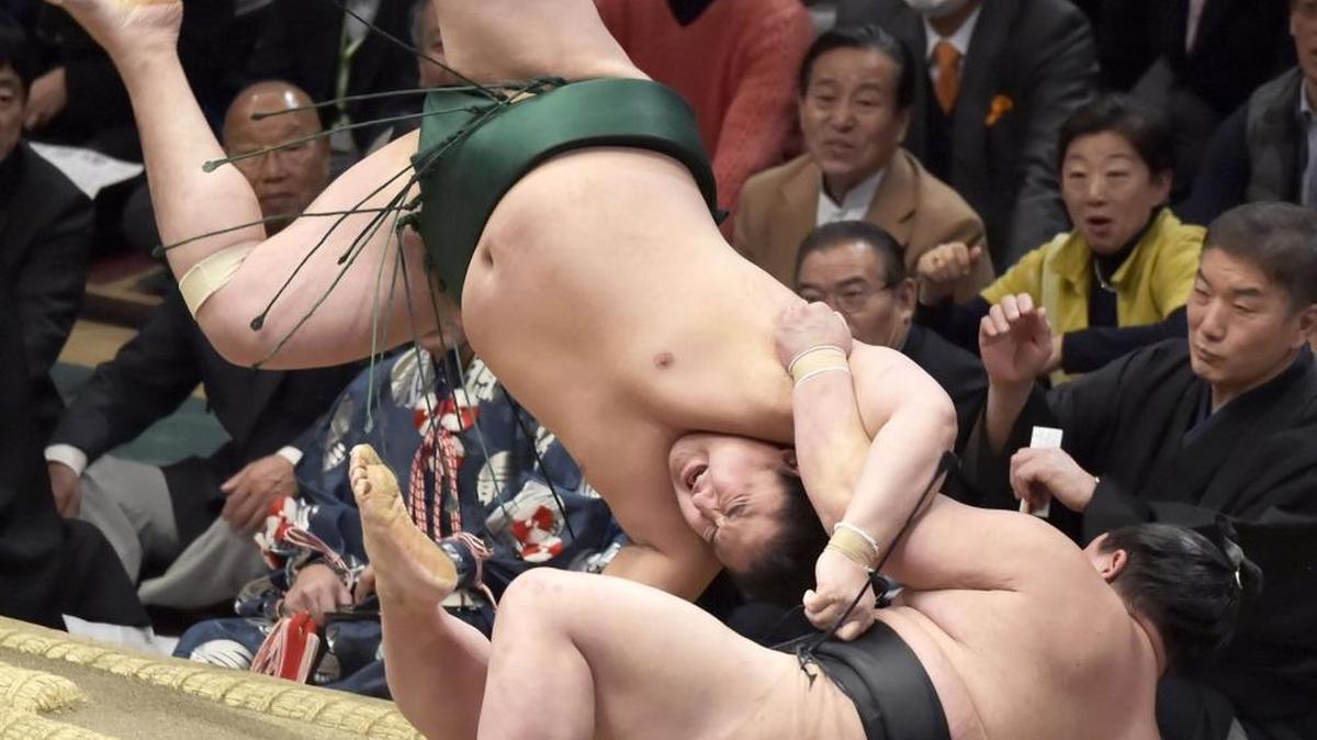 Wrestler Sadanoumi, top, flips as he throws opponent Shodai outside the ring to win their bout in the New Year Grand Sumo Tournament at Ryogoku Kokugikan sumo arena Jan. 17 in Tokyo.