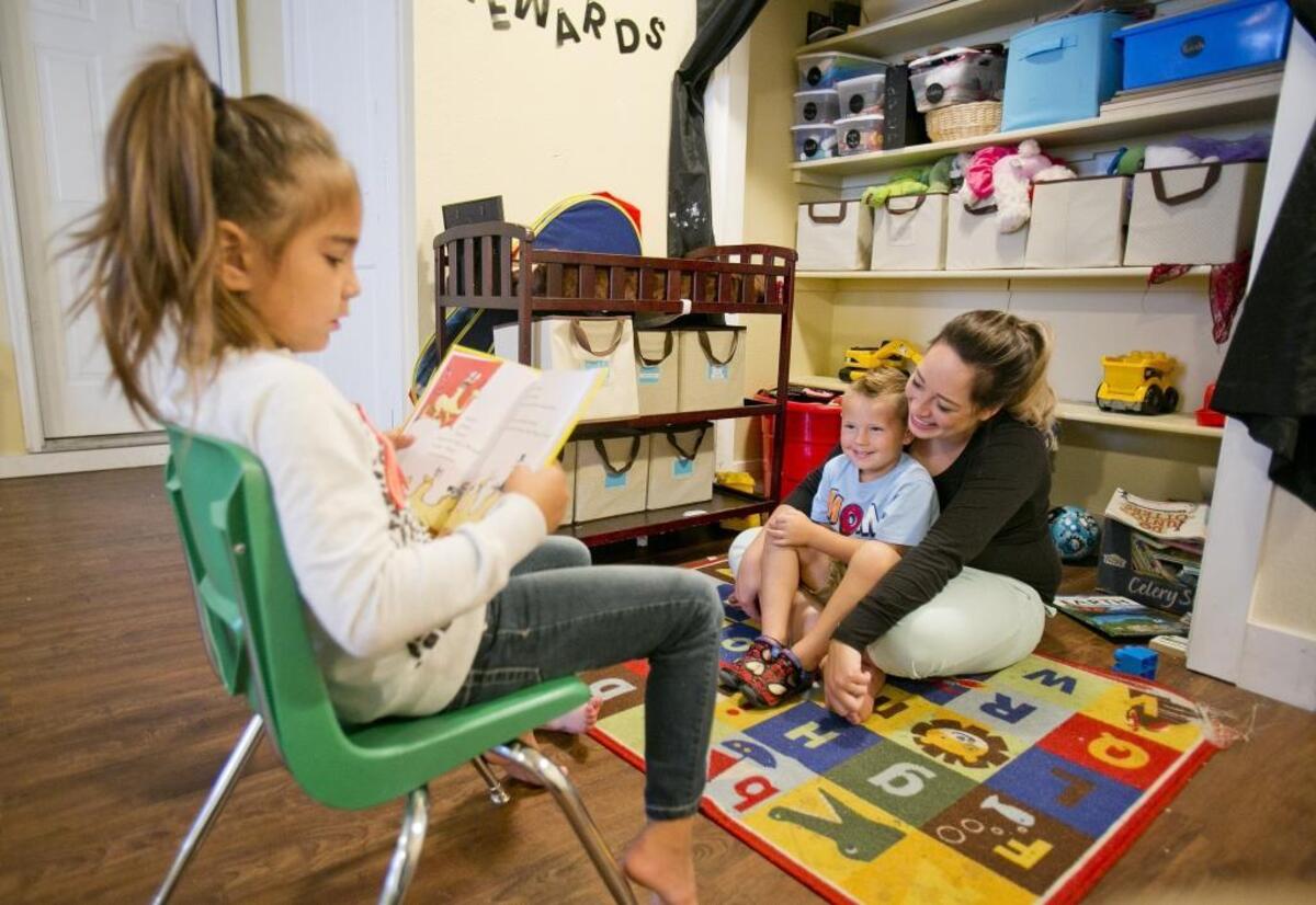 Kim Hill, owner of Silly Monkeys Childcare in Nampa, listens to her daughter read a book while another child sits on her lap during reading time in this file photo.